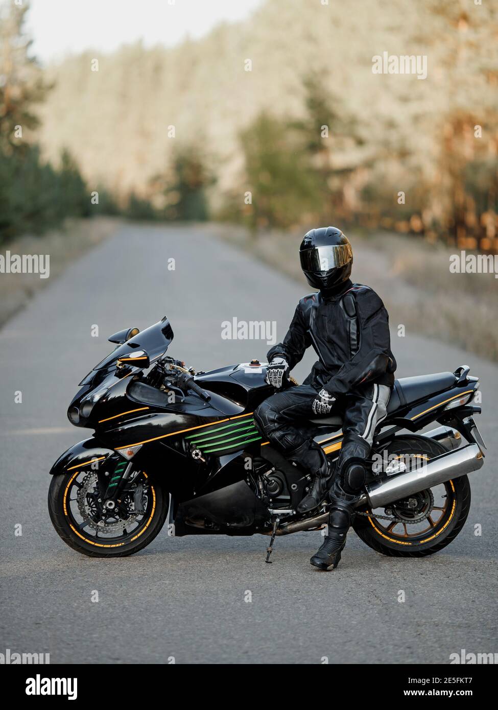 Biker in einem Helm und Leder Schutzausrüstung sitzt auf einem Motorrad, ein sportliches schnelles Motorrad Stockfoto