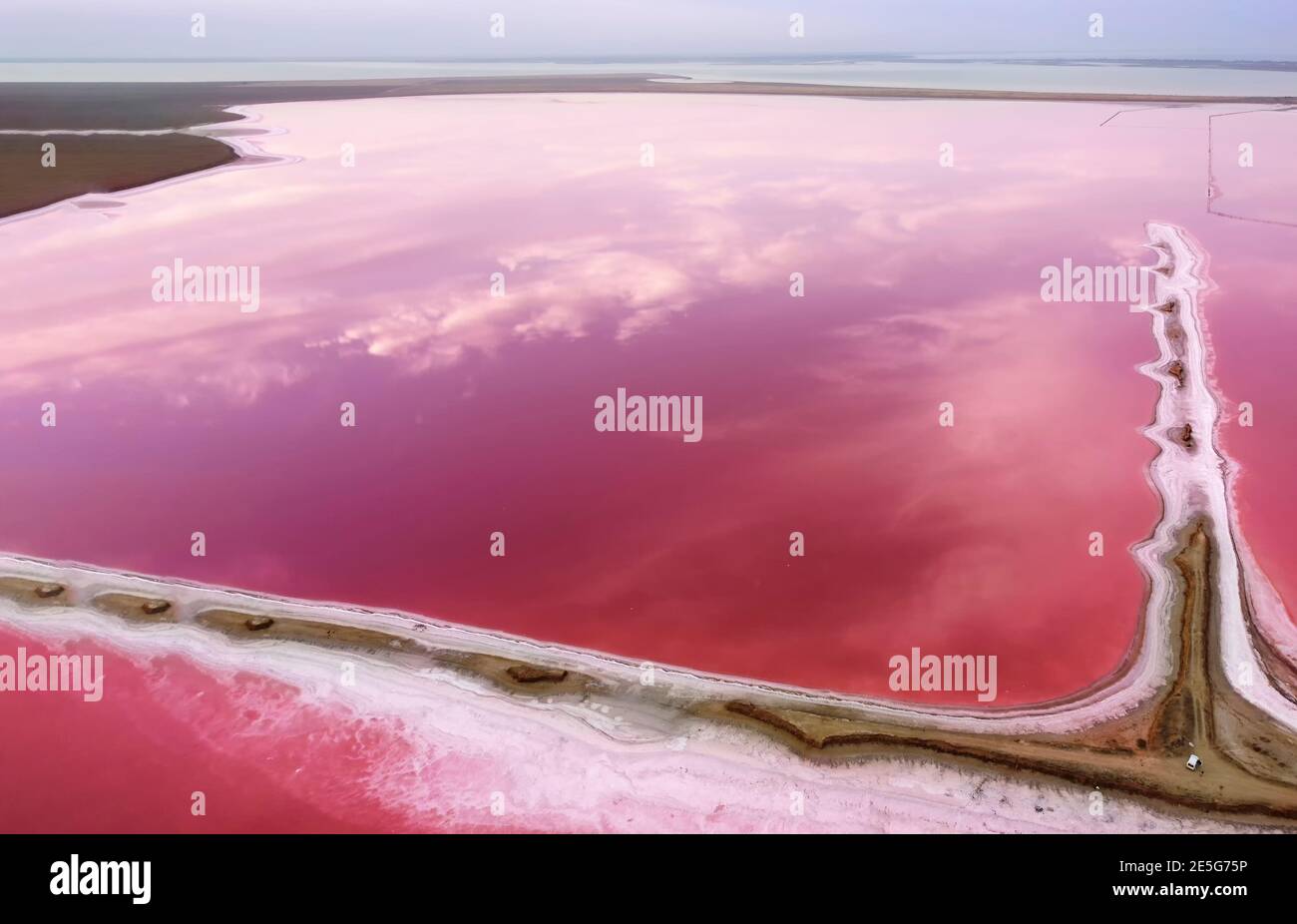 Rosa See und Ufer entlang des Wassers. Spiegelung von Himmelswolken in rosa Wasser. Stockfoto