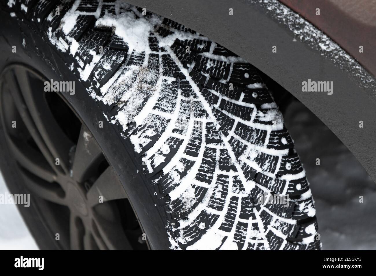 Verschmutztes SUV-Autorad. Schneereifen mit Metallstollen, die die Traktion auf vereisten Oberflächen verbessern, Nahaufnahme mit selektivem Fokus Stockfoto