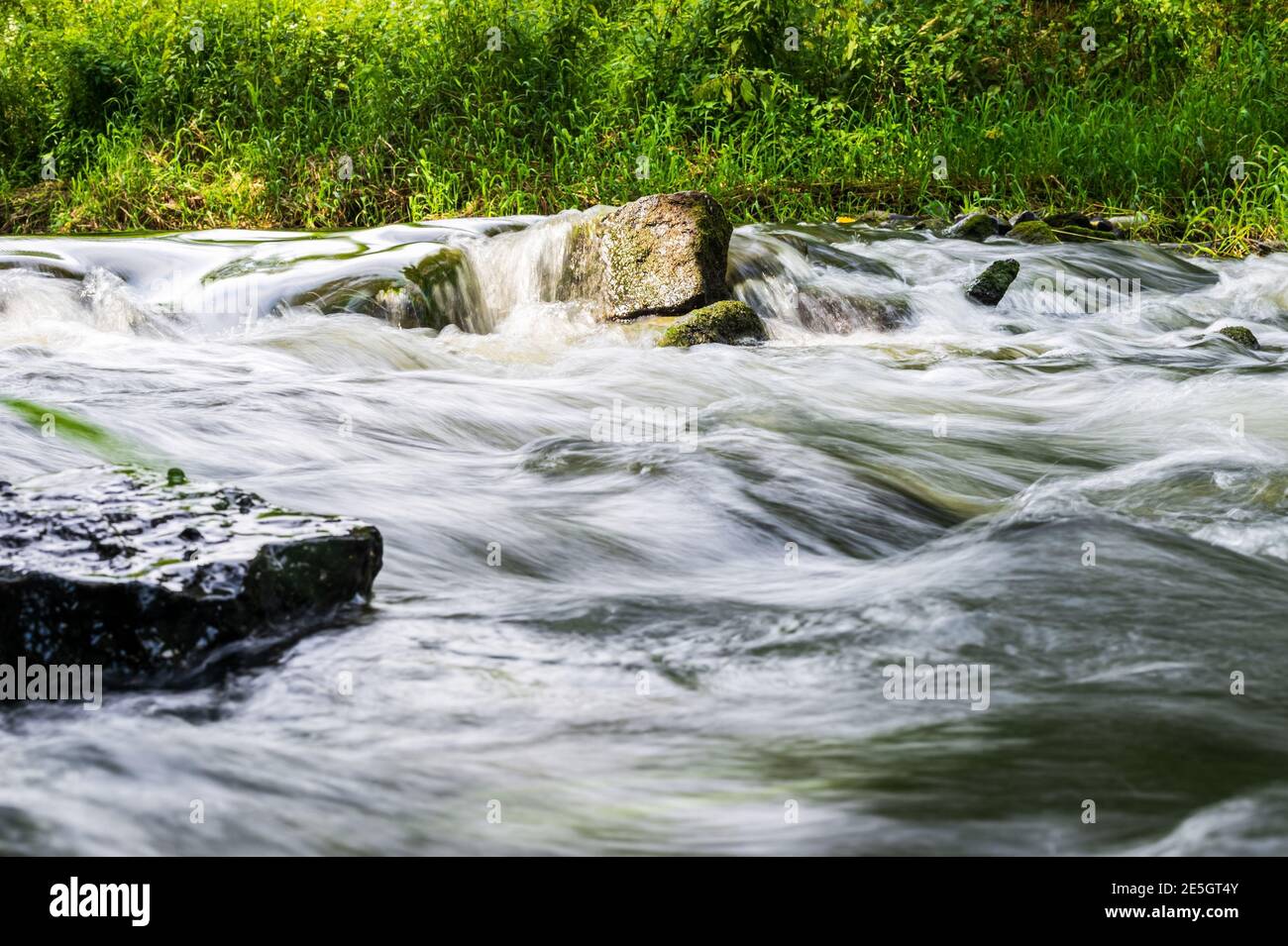 Fluss fließen über Felsen im Sommer Tag. Die Wellen des Flusses fließen. Entspannende Naturlandschaft Landschaft Stockfoto
