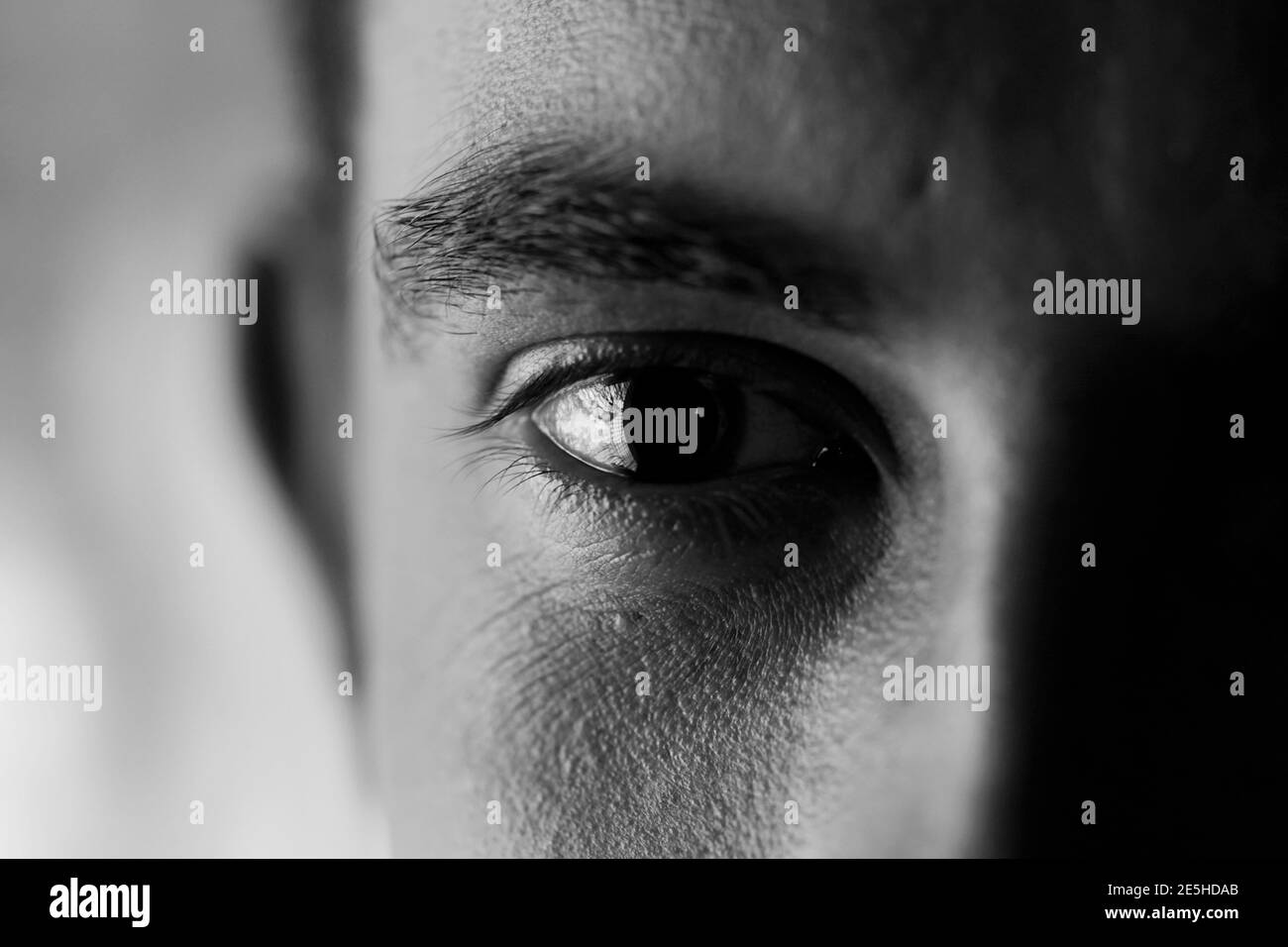 Ausdrucksstarke Optik - Nahaufnahme eines traurig und leer aussehenden Auges, kontrastreiche Schwarz-Weiß-Aufnahme Stockfoto
