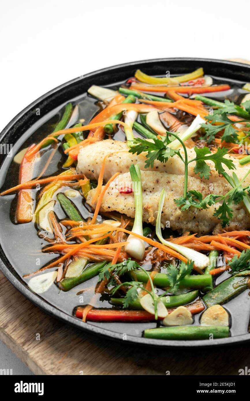 chinesisches, kantonesisches Fischfilet im gedämpften, würzigen Stil mit Gemüse Heizplatte Stockfoto