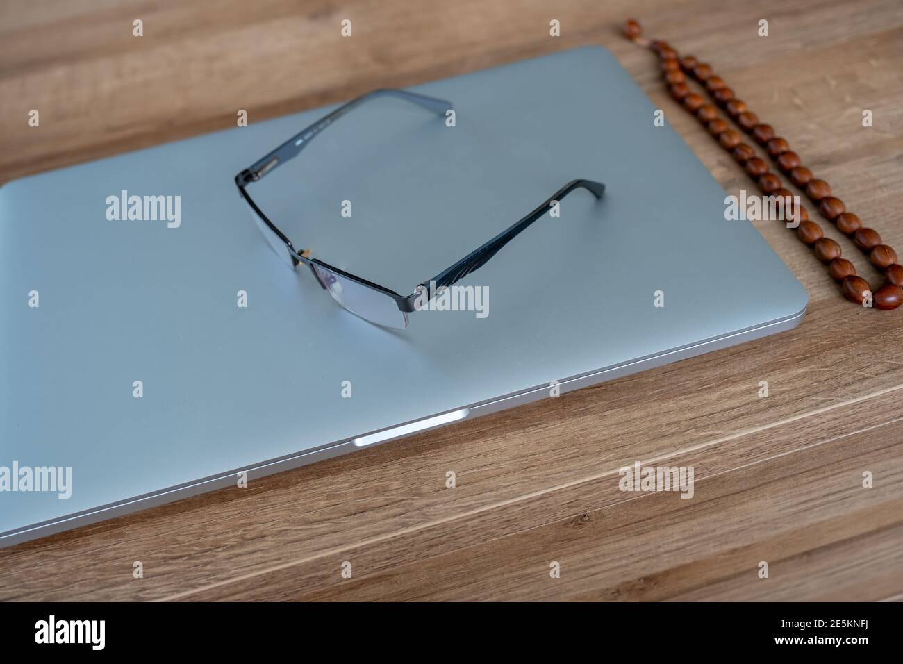 Silberner Laptop und Brille auf dem Tisch Stockfoto
