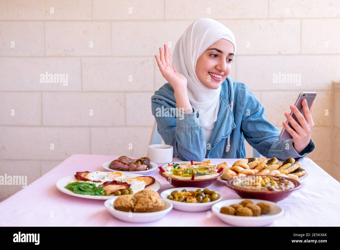 Muslimische Mädchen essen Frühstück und rufen ihre Freunde Stockfoto