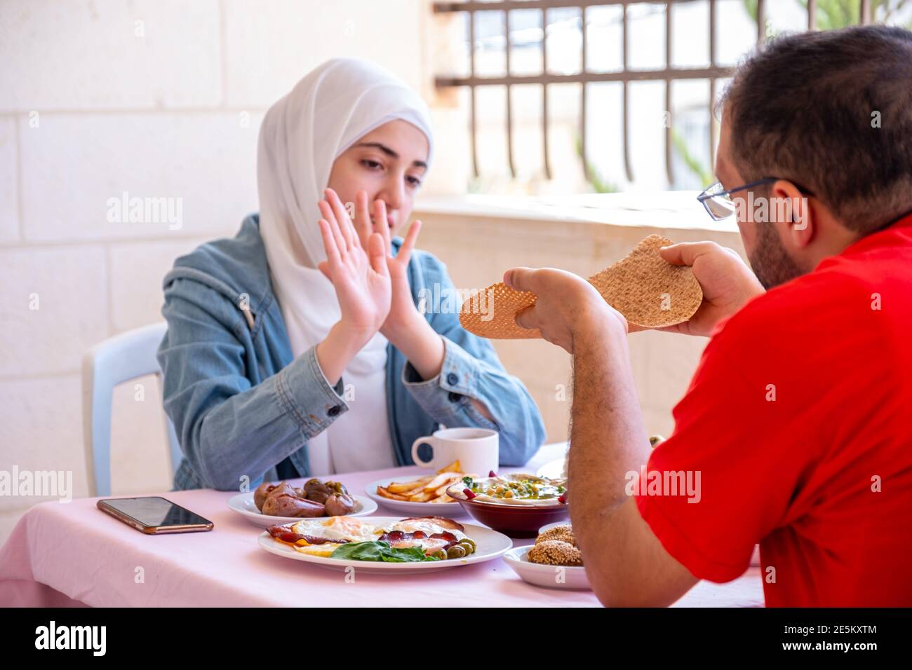 Paare essen zusammen Frühstück und das Mädchen weigert sich Um das Brot zu nehmen Stockfoto