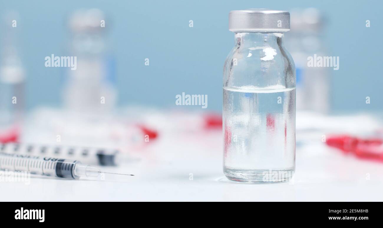 Coronavirus-Impfung. Grippeimpfflasche mit Spritzeninjektion auf blauem Hintergrund mit Kopierraum Stockfoto