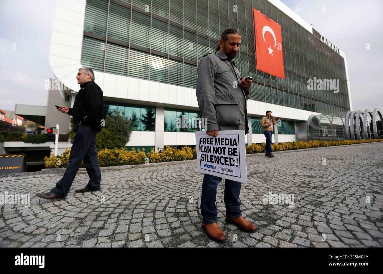 Zaman Media Gruppe Journalist hält einen Banner steht er vor dem Sitz der Tageszeitung Zaman in Istanbul 14. Dezember 2014. Türkische Polizei durchsuchte ein Fernsehsender und eine Zeitung in der Nähe von US-amerikanischen muslimischer Geistlicher Fethullah Gulen am Sonntag, einige Leute verhaften, sagte Medienberichten zufolge, zwei Tage nachdem Präsident Tayyip Erdogan signalisiert eine frische Kampagne gegen Gulens Anhänger. Eine Menge gesungen in den Istanbul-Büros der Zeitung Zaman als Editor vorgenommenen Ekrem Dumanli eine Rede zu ihnen übertragen live im Fernsehen, trotzig fordert Polizei, um ihn festzunehmen. REUTERS/Murad Sezer (TURK Stockfoto