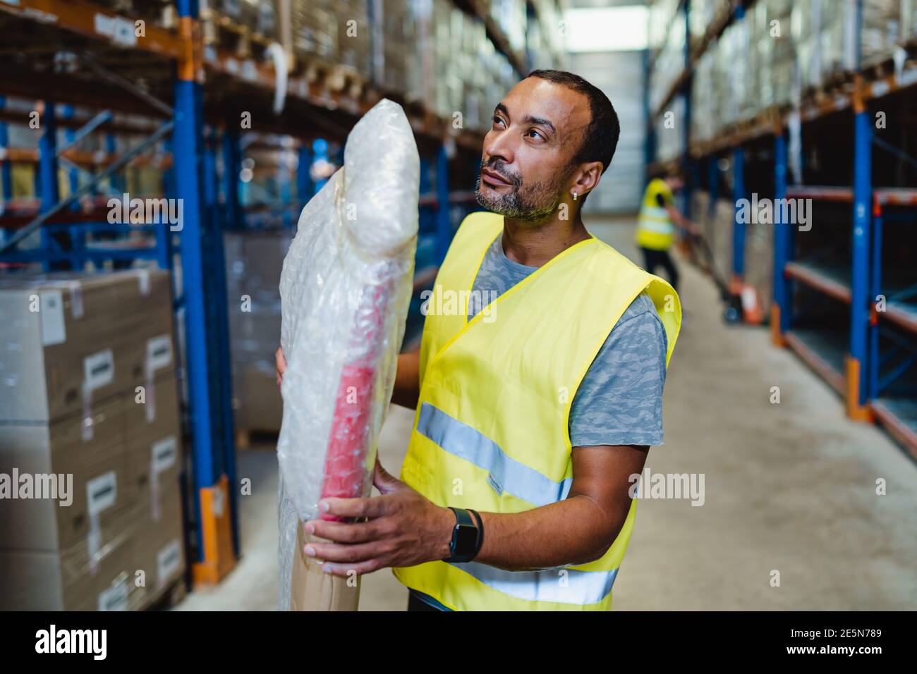 40 Jahre alter afroamerikanischer Arbeiter, der ein Paket einzieht Ein Lager Stockfoto