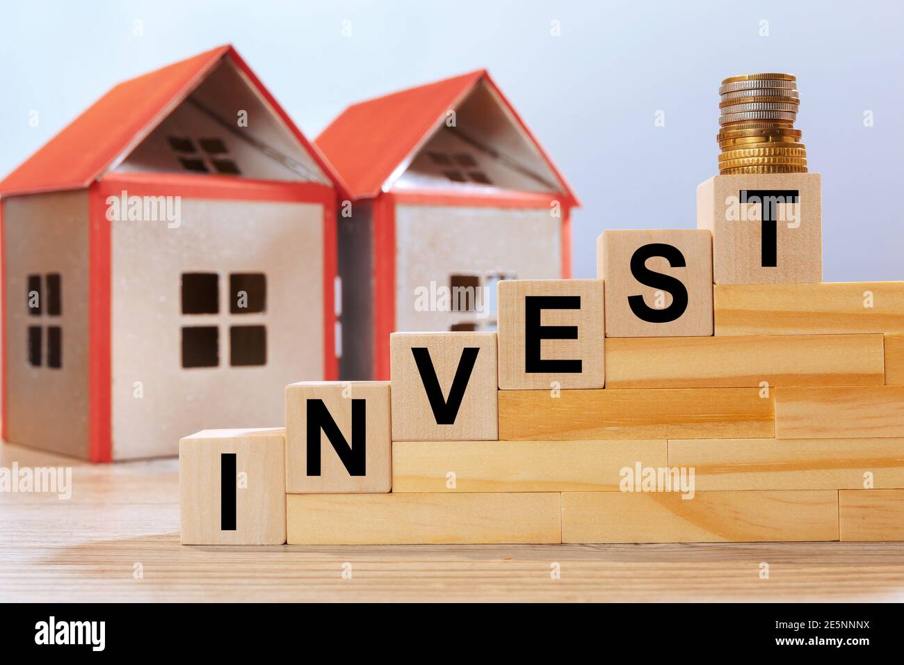 Hausmodelle und Beschriftung auf Holzwürfeln - investieren. Immobilieninvestitionskonzept. Stockfoto