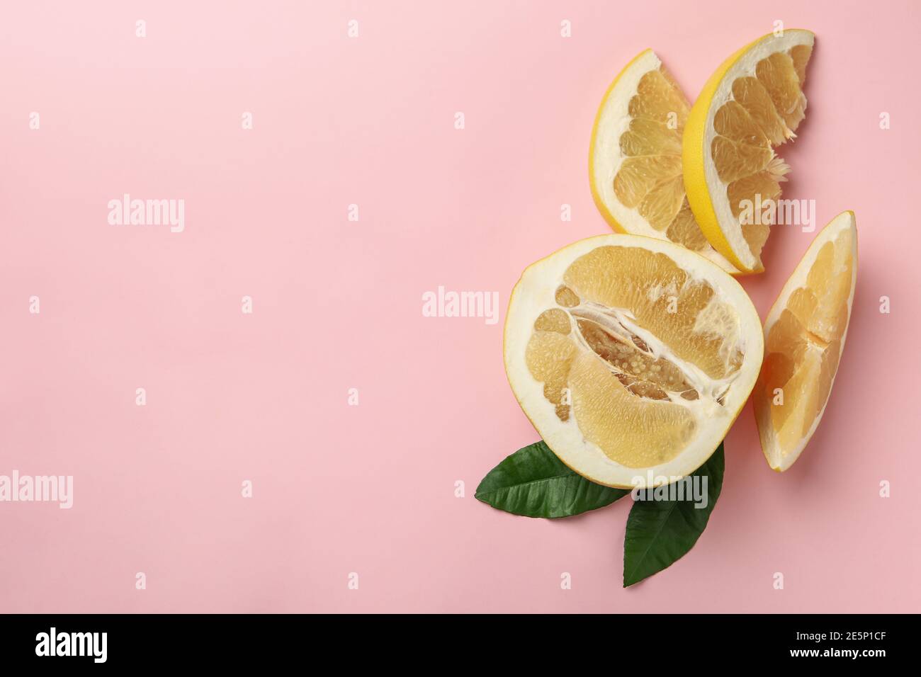 Die Hälfte der Pomelofrucht, Scheiben und Blätter auf rosa Hintergrund Stockfoto