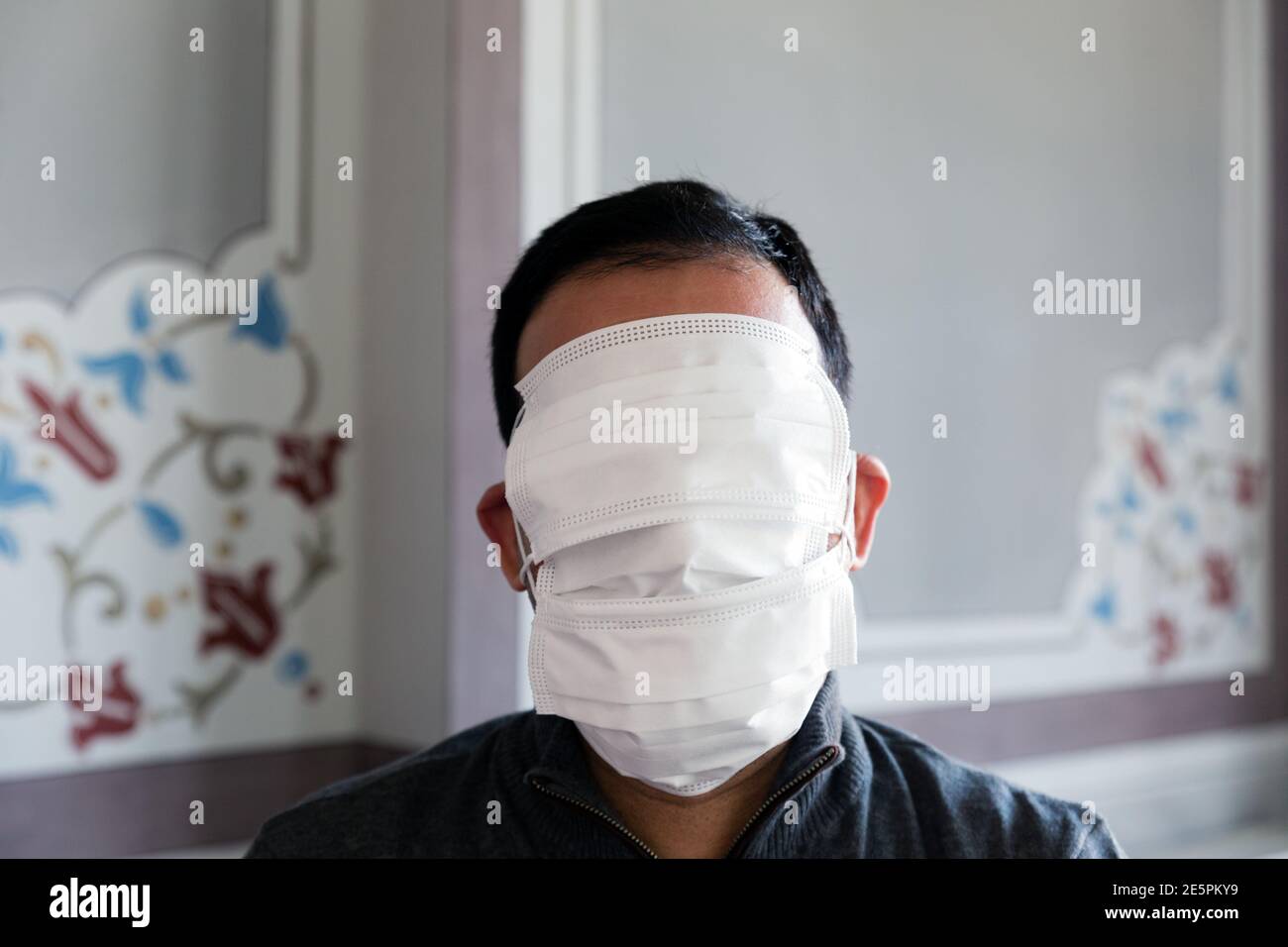 Nicht erkennbarer Erwachsener mit kurzen Haaren mit seinem Gesicht vollständig von Schutzmasken bedeckt, innen Frontportrait aufgenommen Stockfoto