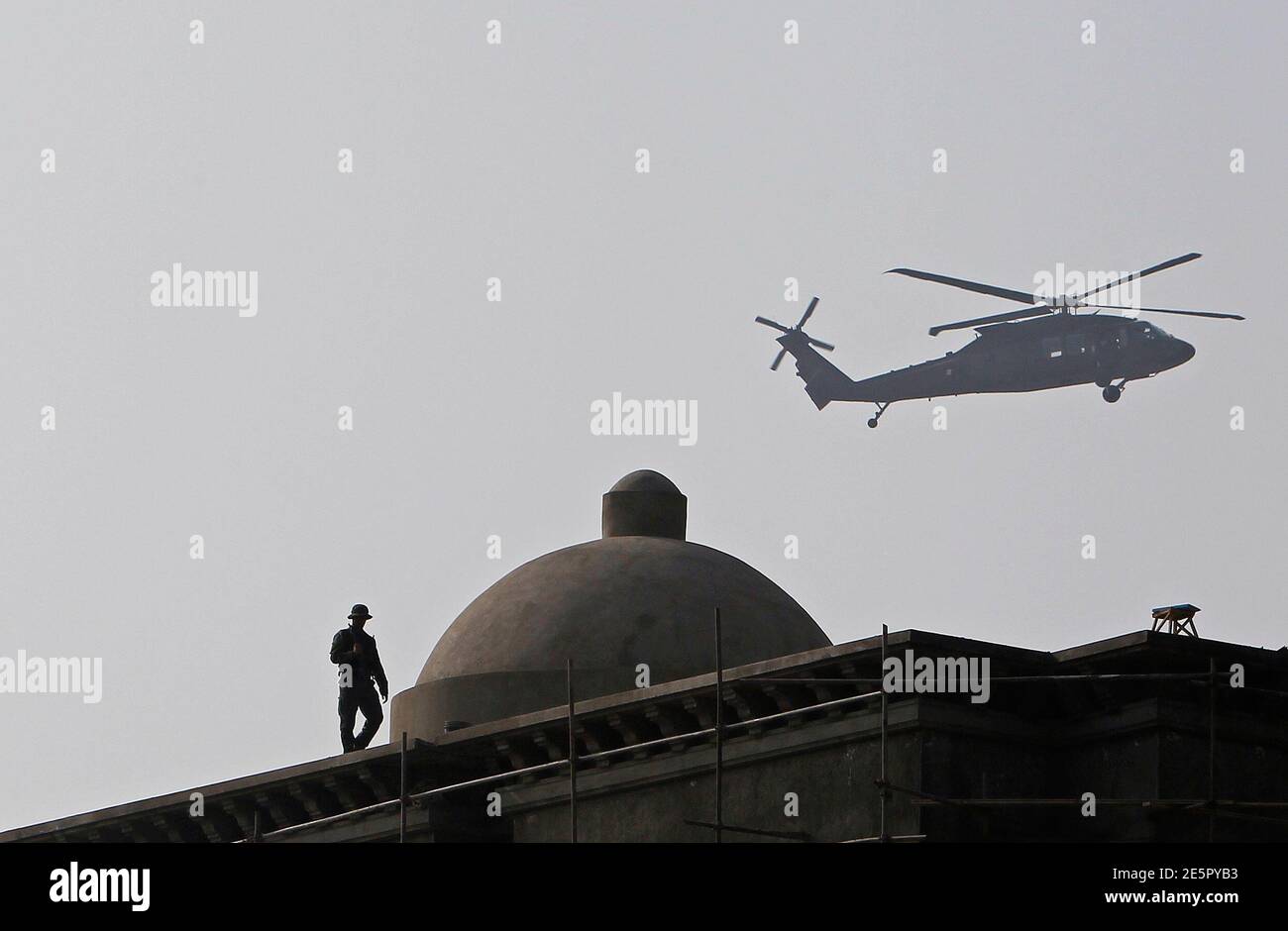 Ein afghanische Wachmann wacht auf dem Dach eines Gebäudes, wie ein NATO-Hubschrauber fliegt, während einer Zeremonie anlässlich der 12. Todestag des ermordeten afghanischen Nationalhelden Ahmad Shah Masood in Kabul 9. September 2013. Massoud oder Löwe von Panjshir gekämpft die Taliban an der Spitze der Nordallianz Afghanistans ethnischen Minderheiten, bis zu seiner Ermordung zwei Tage vor den Anschlägen des 11. September 2001 vertreten. REUTERS/Omar Sobhani (AFGHANISTAN - Tags: Jubiläums-Politik-Militär) Stockfoto