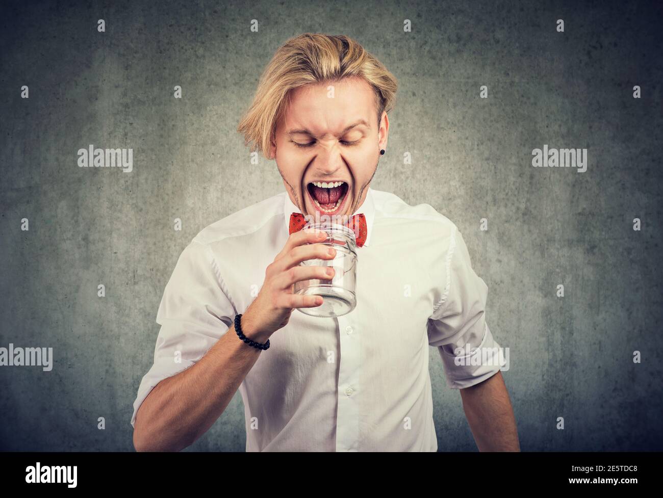 Porträt eines wütenden jungen Mannes, der in leeres Glas schreit Glas Stockfoto