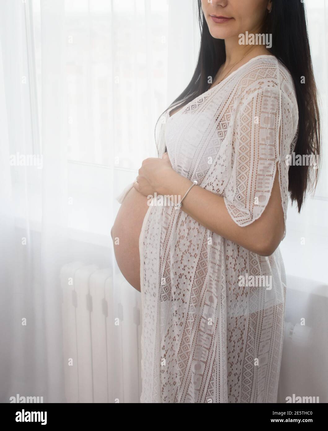 Junge Brünette wartet auf ein Baby in einem weißen vernachlässee Stockfoto
