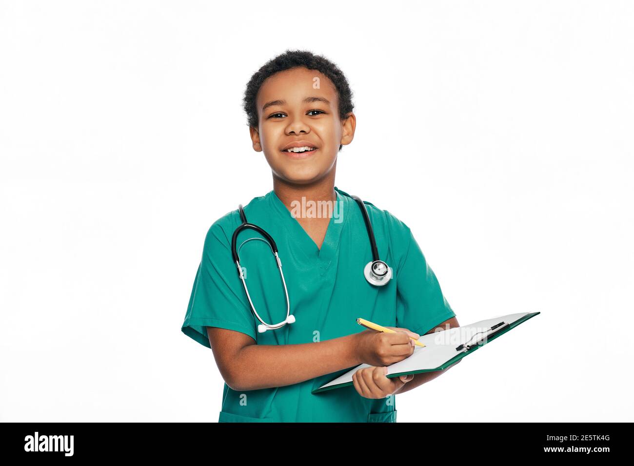 Afroamerikanischer Junge schreibt Gesundheitsbehandlung auf einem medizinischen Klemmbrett. Kind spielt Arzt, zukünftiger Beruf. Weißer Hintergrund Stockfoto