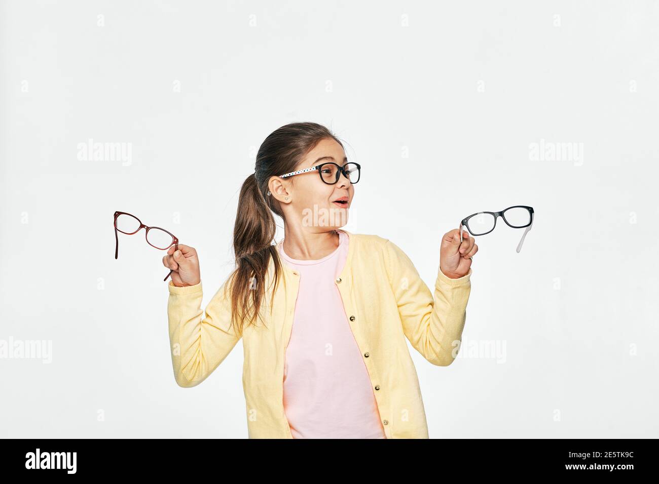 Welche Art von Brillen, um von Kind zu wählen. Lustige asiatische Mädchen tragen Brille mit stilvollen Brillen auf weißem Hintergrund Stockfoto
