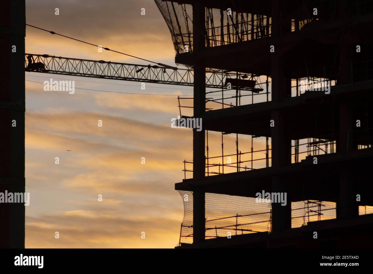 Silhouette eines Gebäudes im Bau mit gelben Wolken an Sonnenuntergang oder Sonnenaufgang Stockfoto