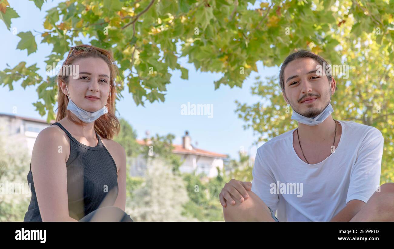 Zwei junge Freunde mit Gesichtsmasken haben Spaß. Treffen mit Freunden im Park während der Coronavirus-Epidemie. Stockfoto