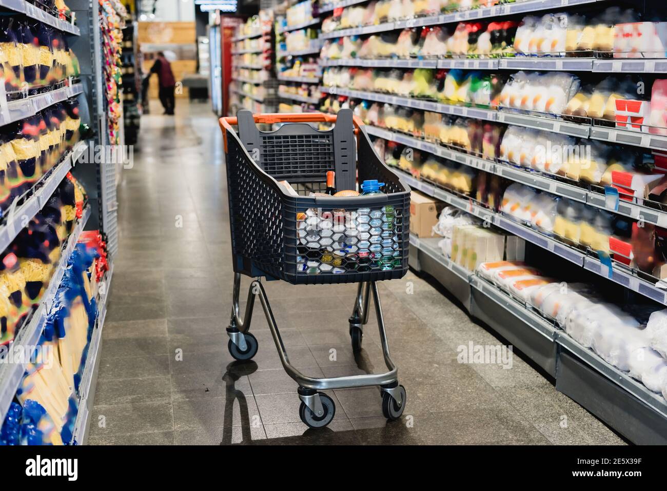 Einkaufswagen in der Nähe von Regalen mit Lebensmitteln im Supermarkt Stockfoto