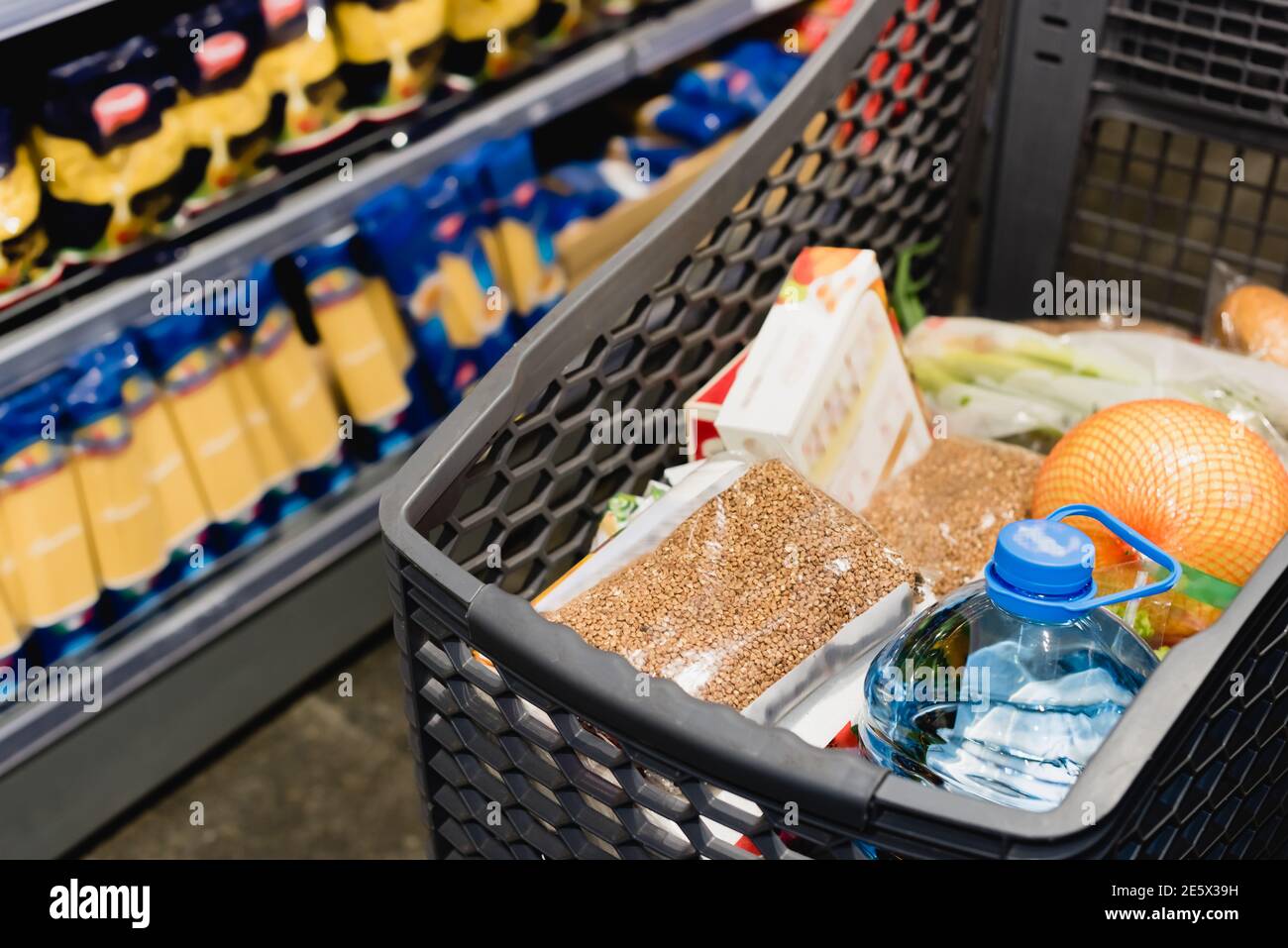 Paket mit Buchweizen und Flasche Wasser im Warenkorb Im Supermarkt Stockfoto
