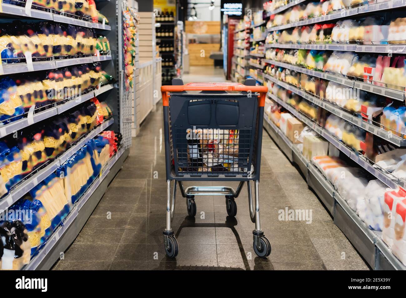 Warenkorb in der Nähe von Lebensmitteln auf Regalen im Supermarkt Stockfoto