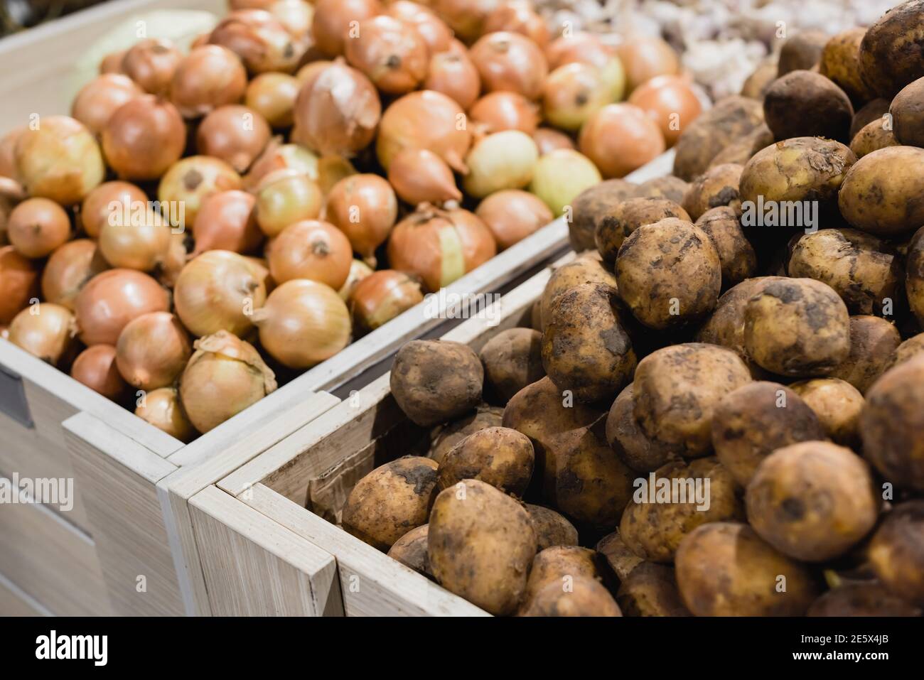 Kartoffeln und Zwiebeln auf verschwommenem Hintergrund im Supermarkt Stockfoto