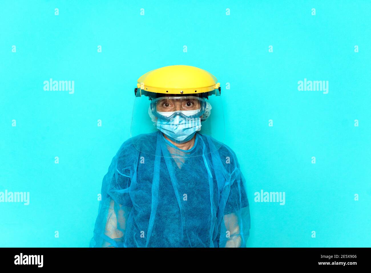 Stock Foto von nicht erkannten medizinischen Arbeiter tragen Schutzkleidung und Helm vor blauem Hintergrund. Stockfoto
