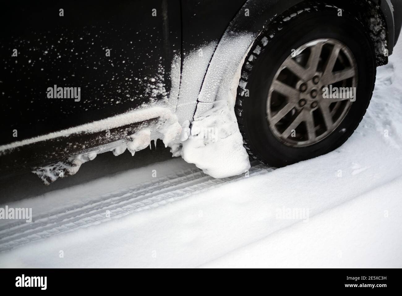 Der Schnee klebte auf einer Karosserie und einem Radbogen Fahren im Winter Stockfoto