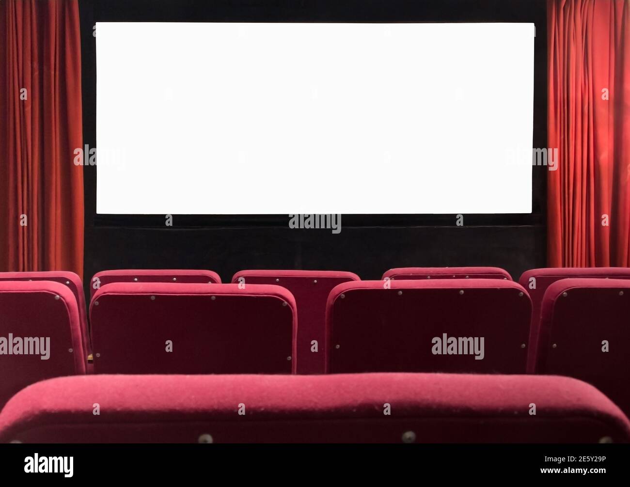 Kinoleinwand mit leeren Sitzen und roten Vorhängen Stockfoto