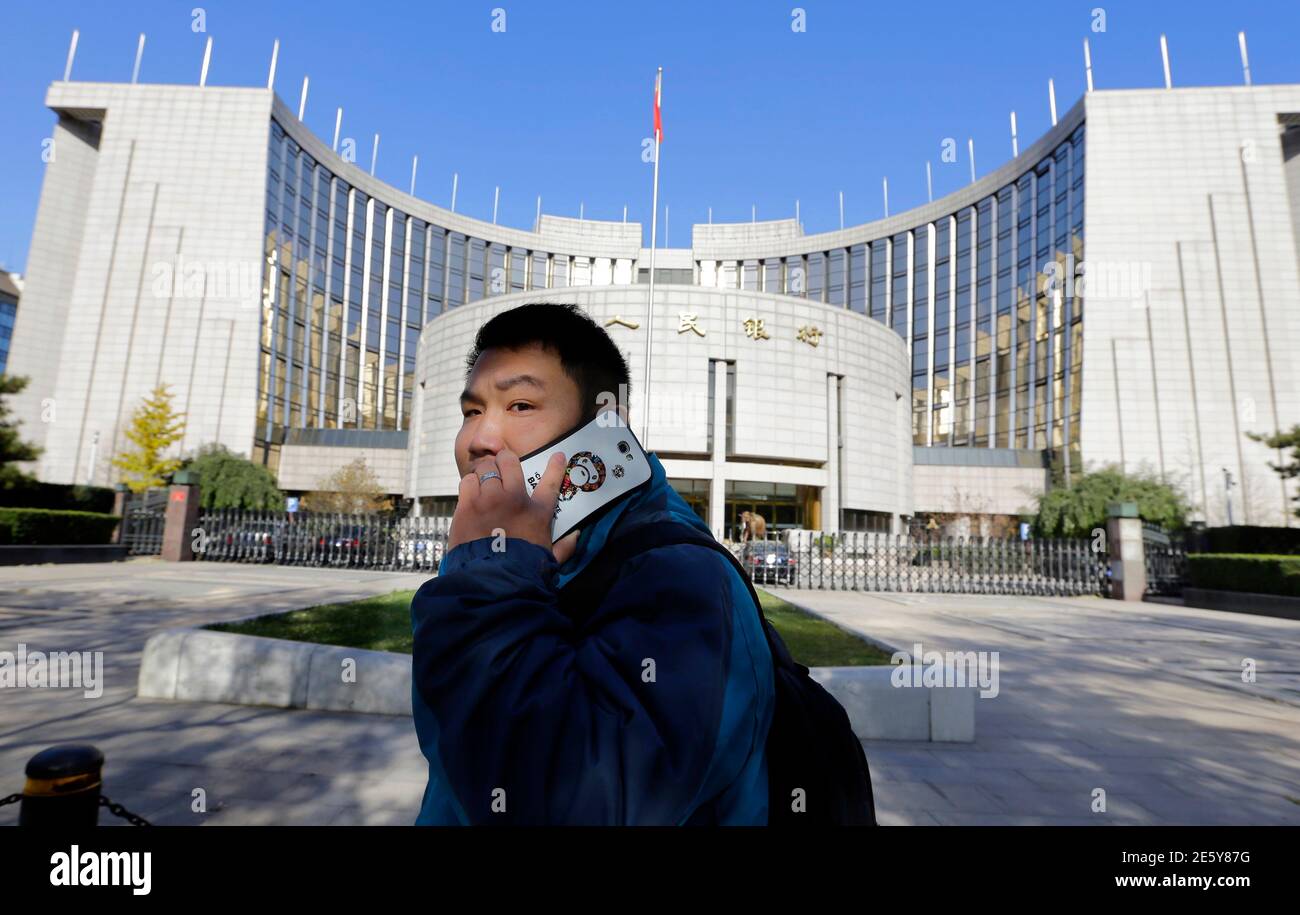 Ein Mann nutzt sein Handy bei einem Spaziergang vorbei an den Hauptsitz von der Volksrepublik Bank of China (PBOC), die Zentralbank in Peking, 20. November 2013. Mit einer Verschiebung in Ton und Sprache hat Chinas Zentralbank-Gouverneur baumelte die Aussicht auf eine Beschleunigung der Währungsreform und und Märkten mehr Platz zum Wechselkurs des Yuan zu setzen, da er größere Pläne für weitreichende wirtschaftliche Veränderungen unterstreicht. Die Zentralbank unter Zhou Xiaochuan hat konsequent seine Absicht, die Liberalisierung der Finanzmärkte und erlauben die Yuan, frei, noch vor der kommunistischen Partei Chinas Führungsriege enthüllt Lat Handel gekennzeichnet Stockfoto