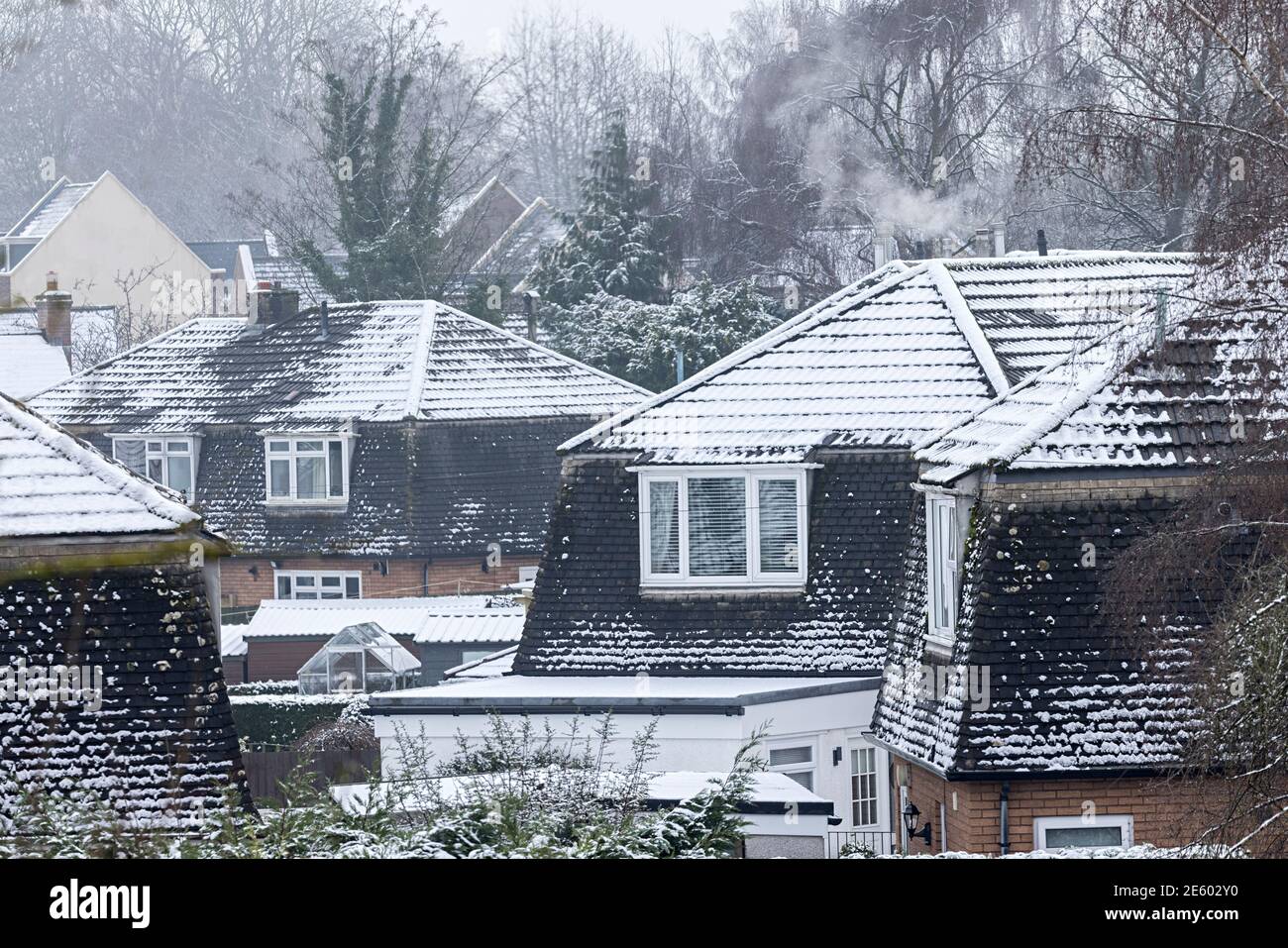 Schnee auf Dächern im Dorf mit Rauch aus Schornstein, Llanfoist, Wales, UK Stockfoto