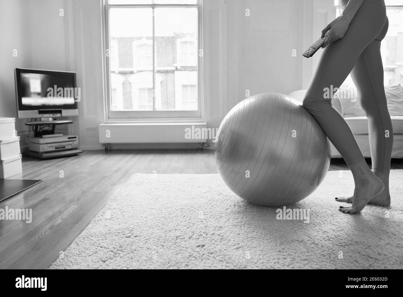 Schwarz-Weiß-Foto einer jungen Frau, die bei der Fitness steht Ball zu Hause beim Lockdown Stockfoto