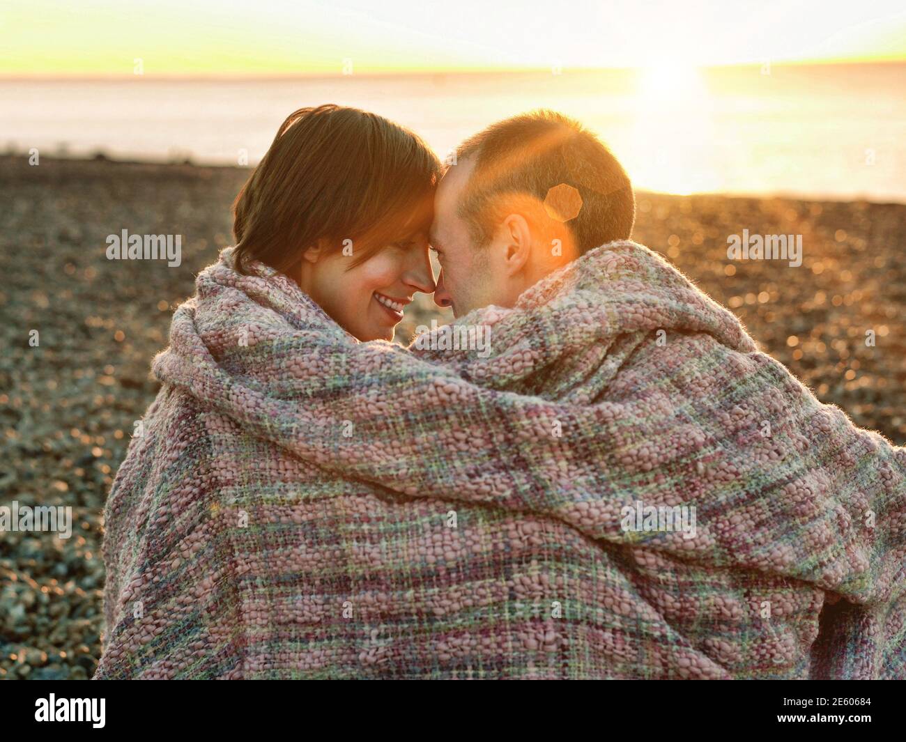 Nahaufnahme eines Paares, das sich umhüllt ansieht In Decke am Strand Stockfoto