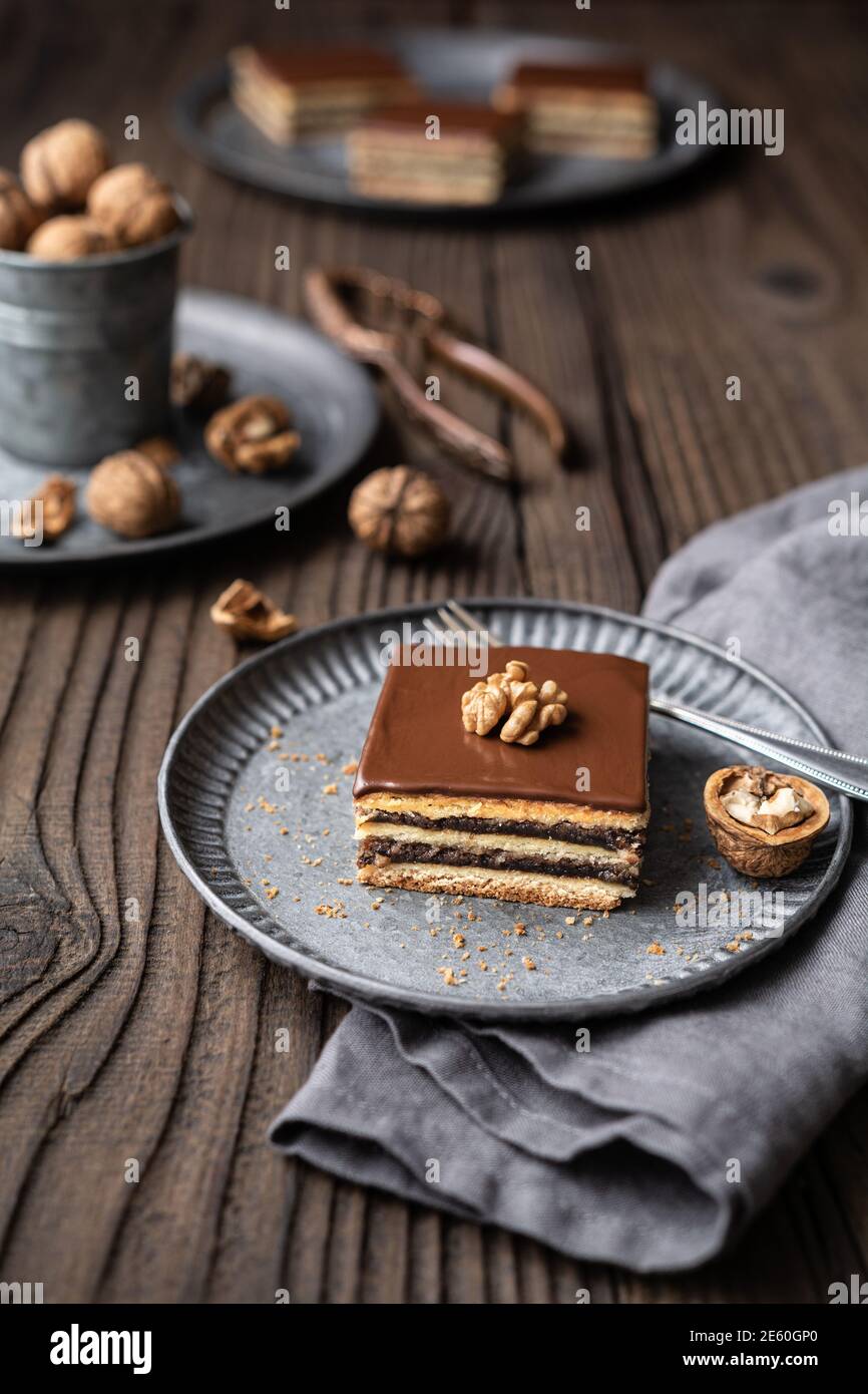 Gerbeaud Bars gefüllt mit Pflaumenmarmelade und zerkleinerten Walnüssen, gekrönt mit Schokolade Zuckerguss auf Holzgrund Stockfoto