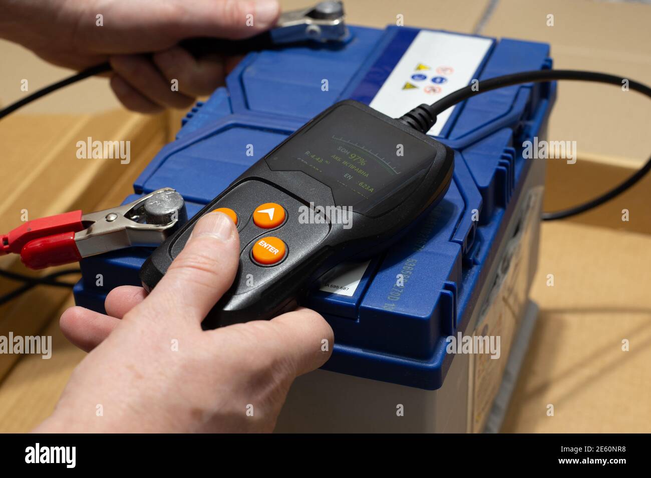 Der Mensch führt die Diagnose der Autobatterie mit dem Tester, der Nahaufnahme durch. AKB gute Übersetzung Stockfoto
