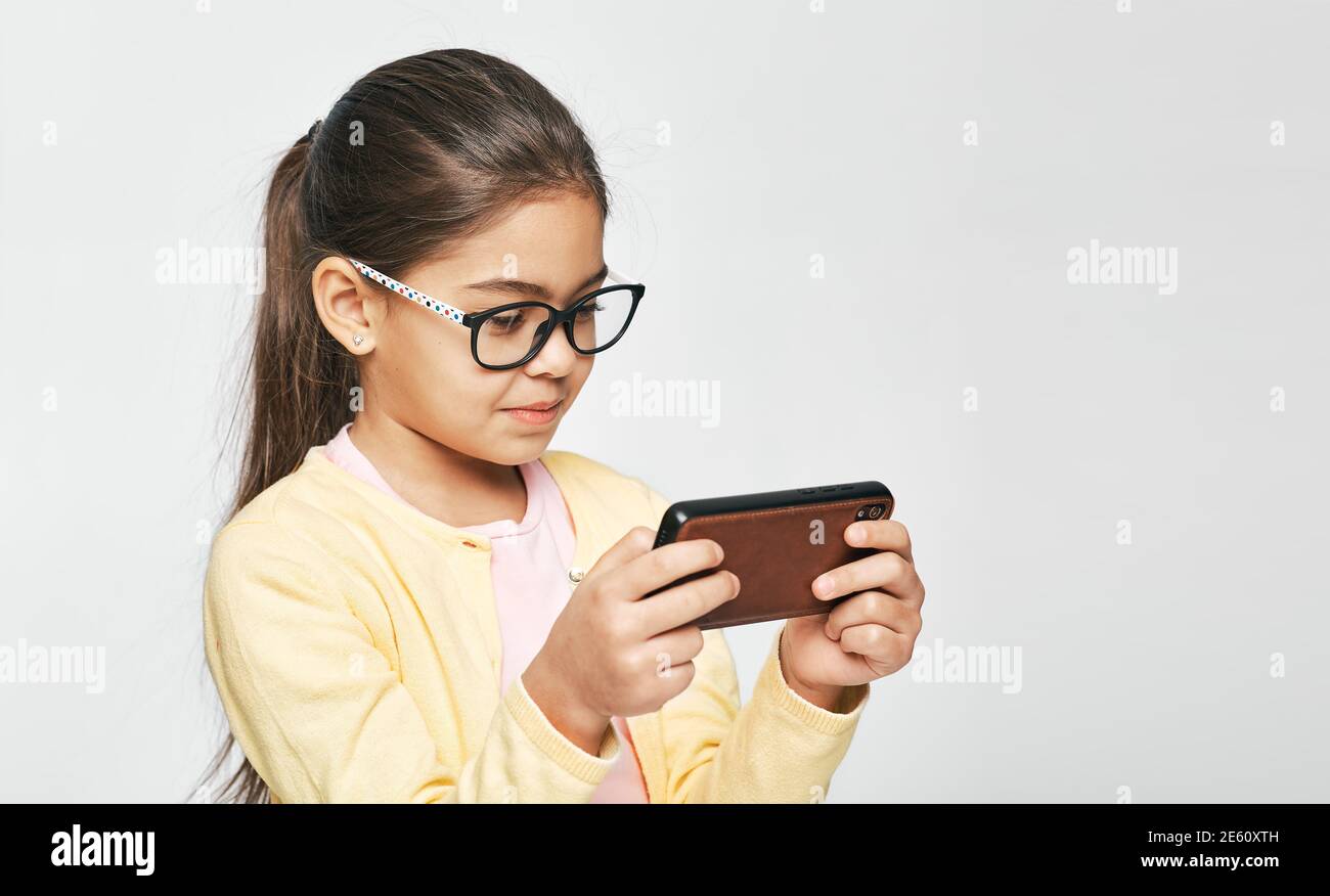 Smartphone-Nutzung, Augenschäden bei Kindern verursachen. Kind trägt Brillen schaut auf Smartphone Stockfoto