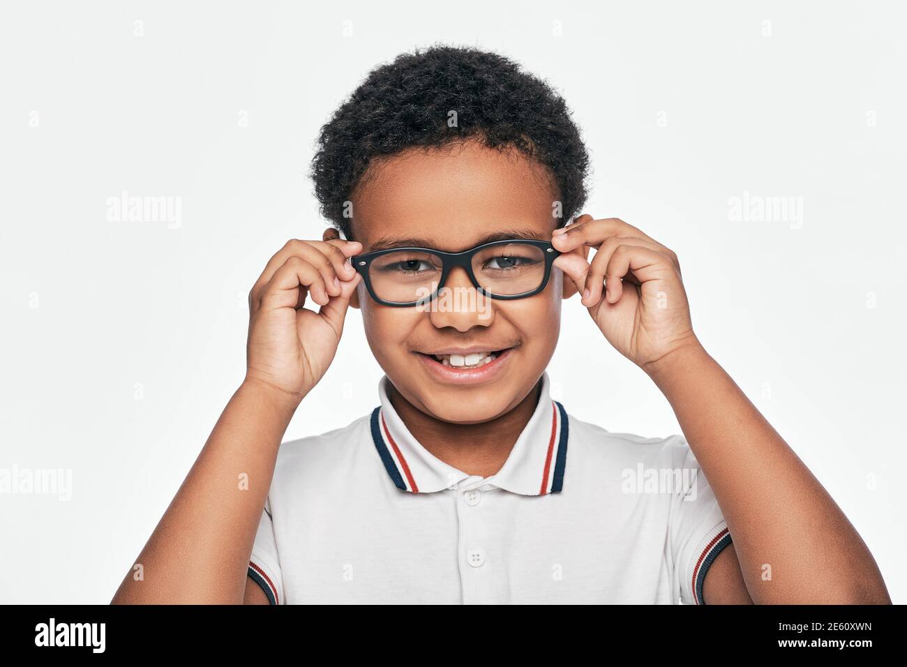 Afroamerikanischer kleiner Junge, der stilvolle Brillen justiert, die Kamera betrachtet, isoliert auf weißem Hintergrund Stockfoto