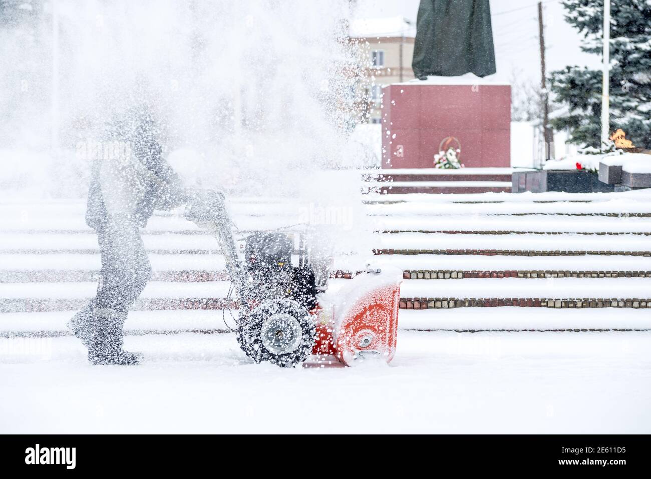 Schnee - Ausbau der Arbeit mit einer Schneefräse. Mann aus Schnee. von Starkniederschlägen und Schnee Stapel Stockfoto