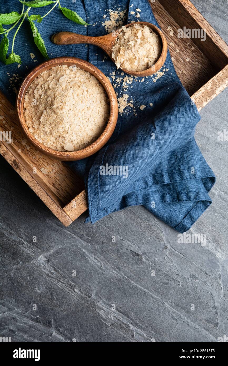 Nahrungsergänzungsmittel, unfortifizierte Hefe-Flocken in einer Holzschale und Schaufel auf Stein Hintergrund mit Copy Space Stockfoto