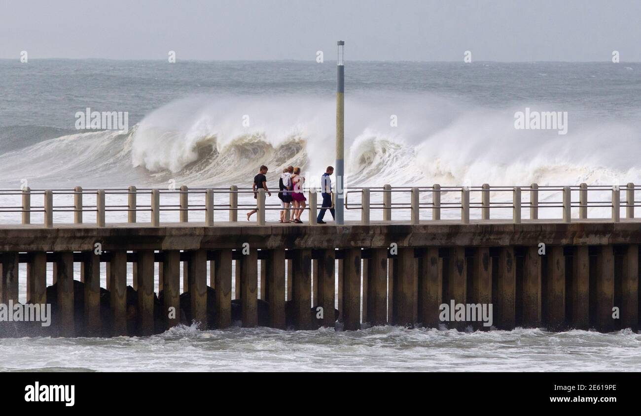 Menschen zu Fuß auf einem Pier, bei großen Wellen verursacht durch Hurrikan Irina das einige 200 Seemeilen vor Durban 5. März 2012 sitzt zu suchen. REUTERS/Rogan Ward (Südafrika - Tags: Umgebung) Stockfoto