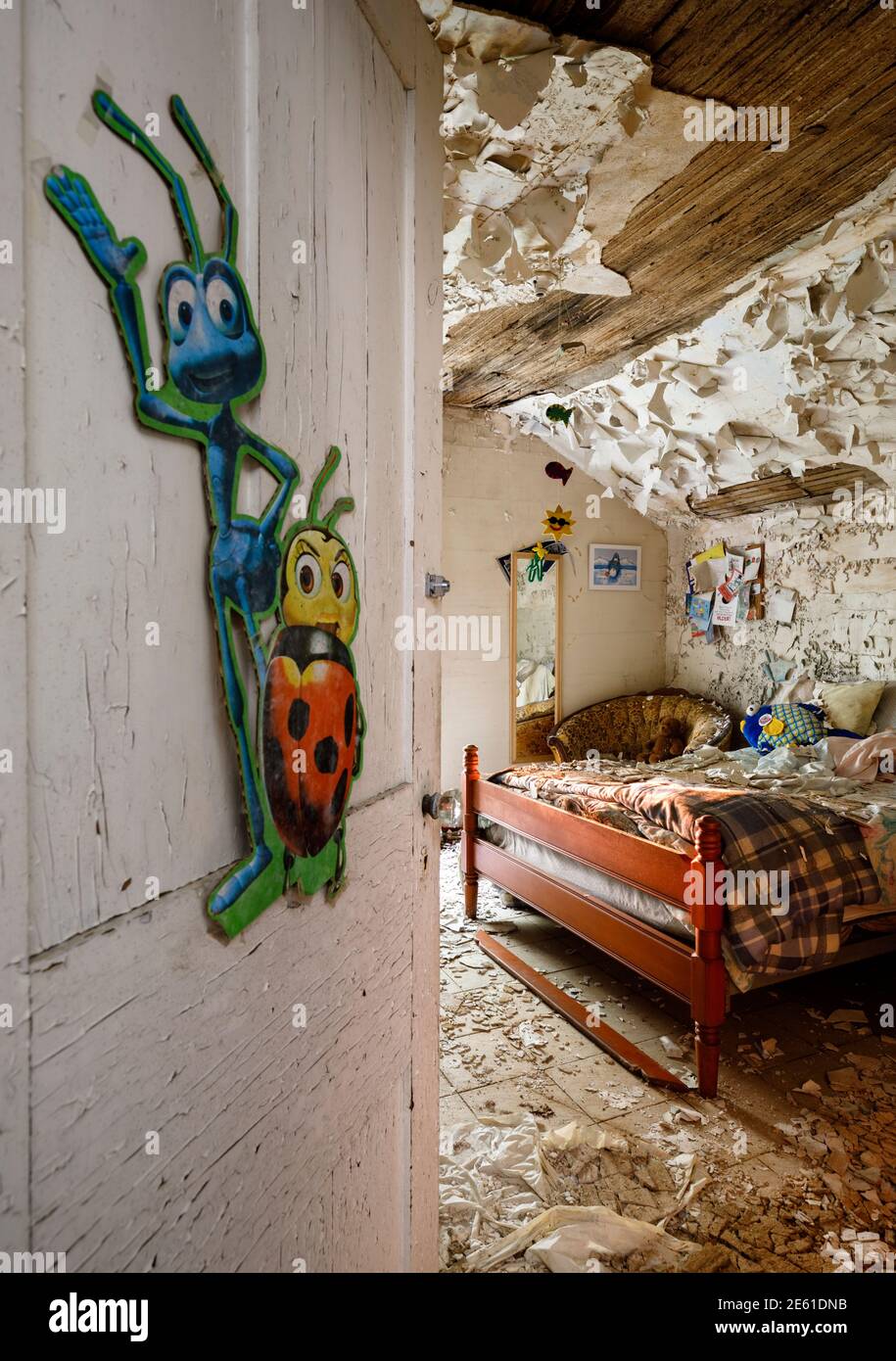 Ein unordentliches Schlafzimmer in einem verlassenen Haus mit Kinderspielzeug und Kunstwerken an den Wänden und abblätternder Farbe. Ontario, Kanada. Stockfoto