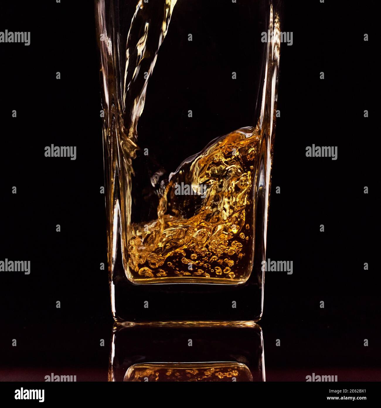 Nahaufnahme des Gießen von frischem Apfelsaft in das Glas. Schwarzer Hintergrund. Zeitlupe. Gesunde Lebensmittel, Vitamine, Früchte Stockfoto