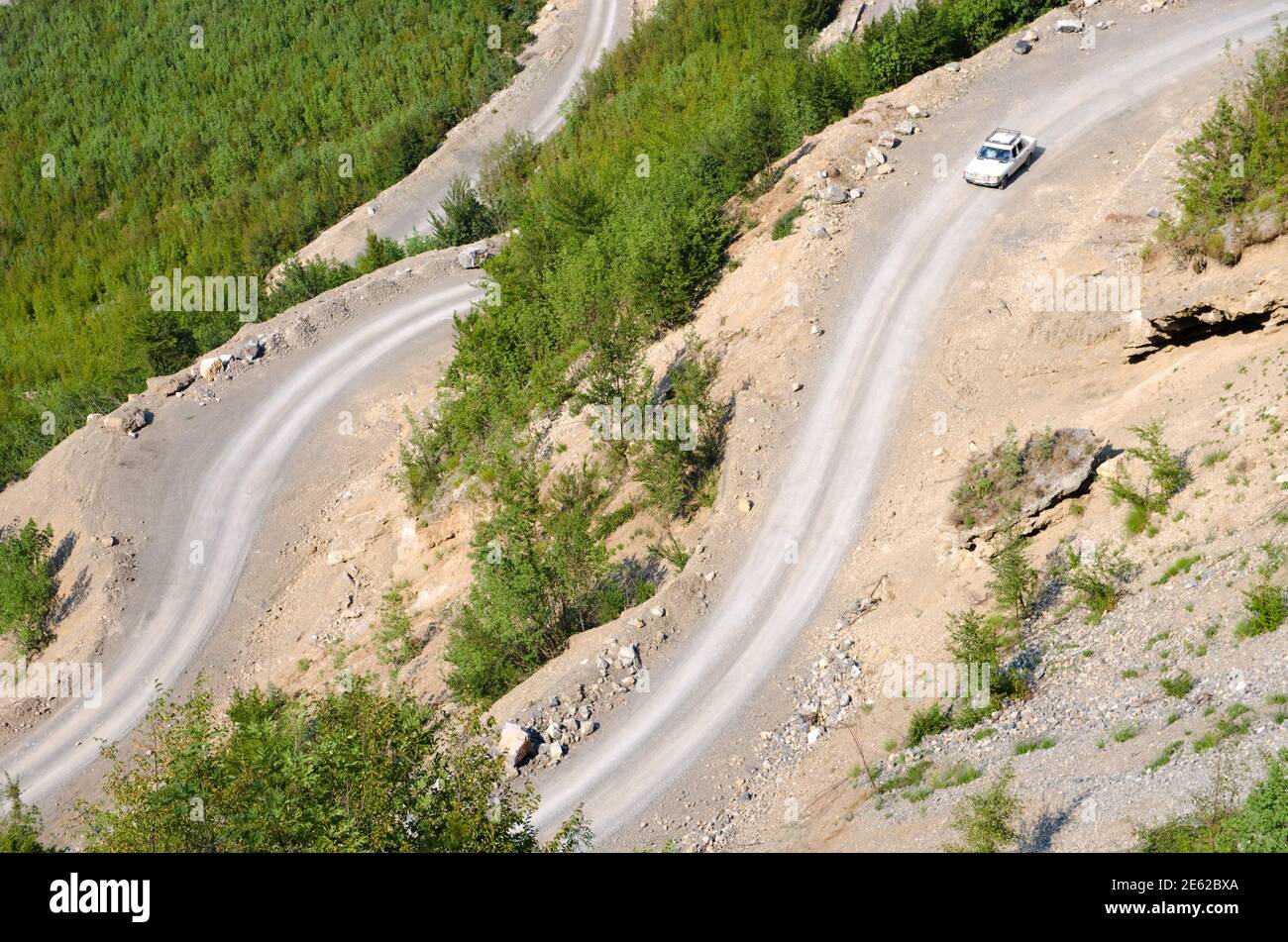 Ein alter mercedes fährt auf dem kurvenreichen Dreck bergab Straße in das Tal des Kelmend zwischen den albanern Berge Stockfoto