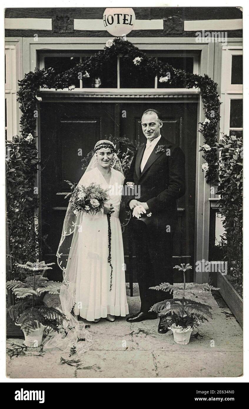 DEUTSCHLAND - UM 1930s: Vintage-Foto von Jungvermählten. Braut trägt weiße Kleidung. Der Bräutigam trägt elegante Kleidung und eine weiße Fliege. Außenfoto. Hochzeit 1930s. Stockfoto