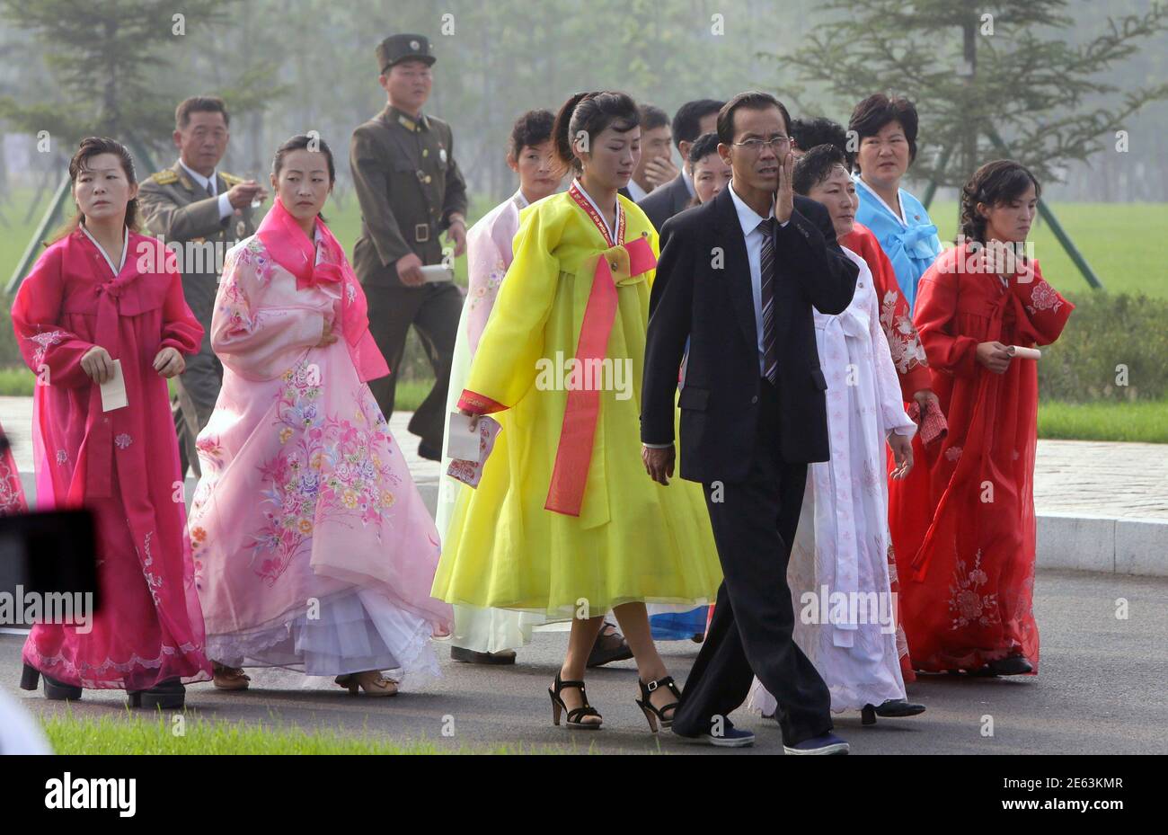 Nordkoreanische Frauen in traditionellen Kostümen und Soldaten kommen zur Eröffnungszeremonie des Friedhofs der Gefallenen Kämpfer der koreanischen Volksarmee (KPA) in Pjöngjang am 25. Juli 2013, Im Rahmen der Feierlichkeiten vor dem 60. Jahrestag der Unterzeichnung eines Waffenstillstands im Koreakrieg 1950-1953. REUTERS/Jason Lee (NORDKOREA - Tags: JAHRESTAG MILITÄRPOLITIK) Stockfoto