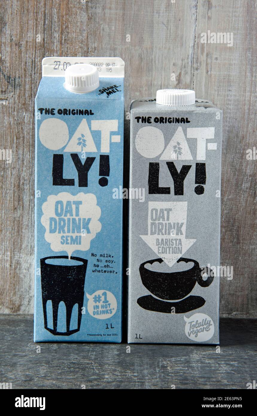 Zwei Kartons mit Oatly veganer Hafermilch oder -Getränk; die Original Oatly Semi und die Barista Edition vor Holzhintergrund Stockfoto