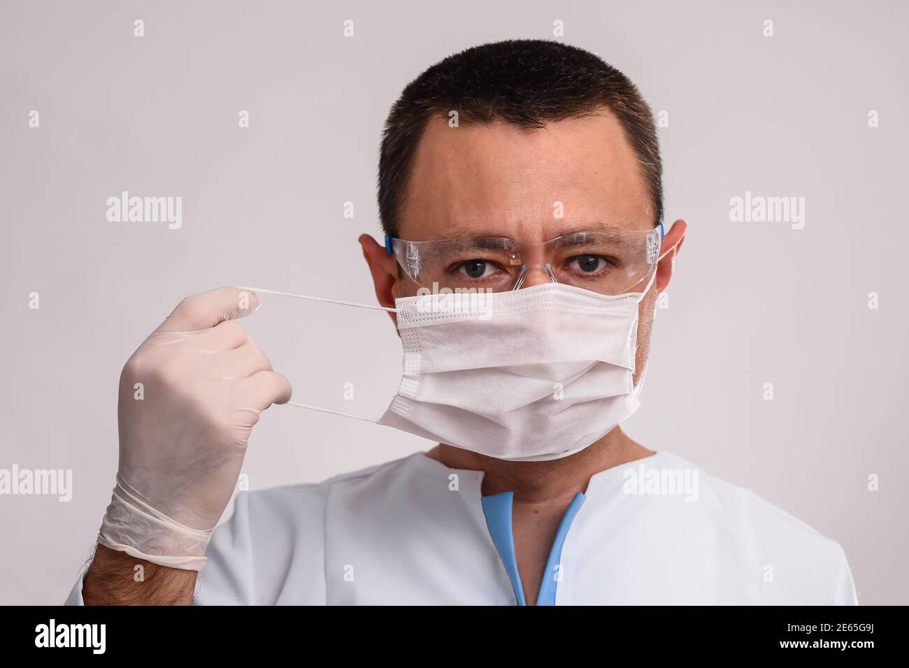 Professioneller Arzt, der eine schützende Gesichtsmaske aufsetzt. COVID-19 Präventivmaßnahmen. Stockfoto