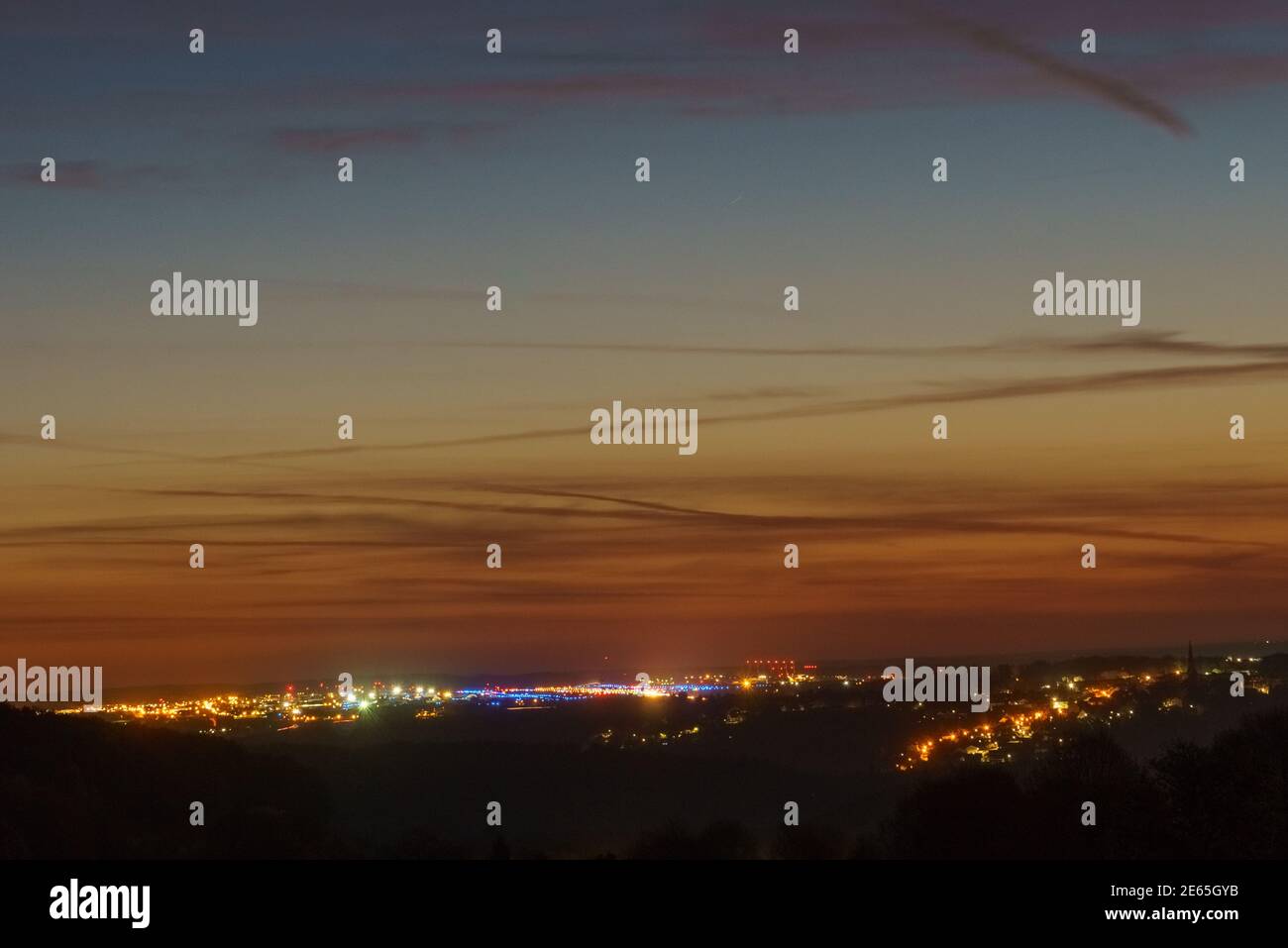 Frühmorgendliche Morgendämmerung mit buntem Himmel über den Lichtern des luftstützpunktes spangdahlem, deutschland Stockfoto