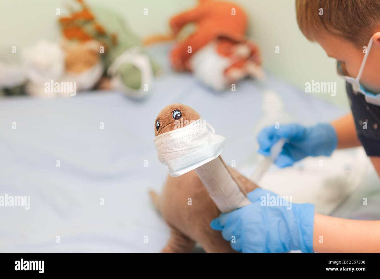 Kind spielt Rollenspiele. Kleiner Arzt impft Spielzeug-Patient Junge behandelt Dinosaurier, Nahaufnahme Stockfoto