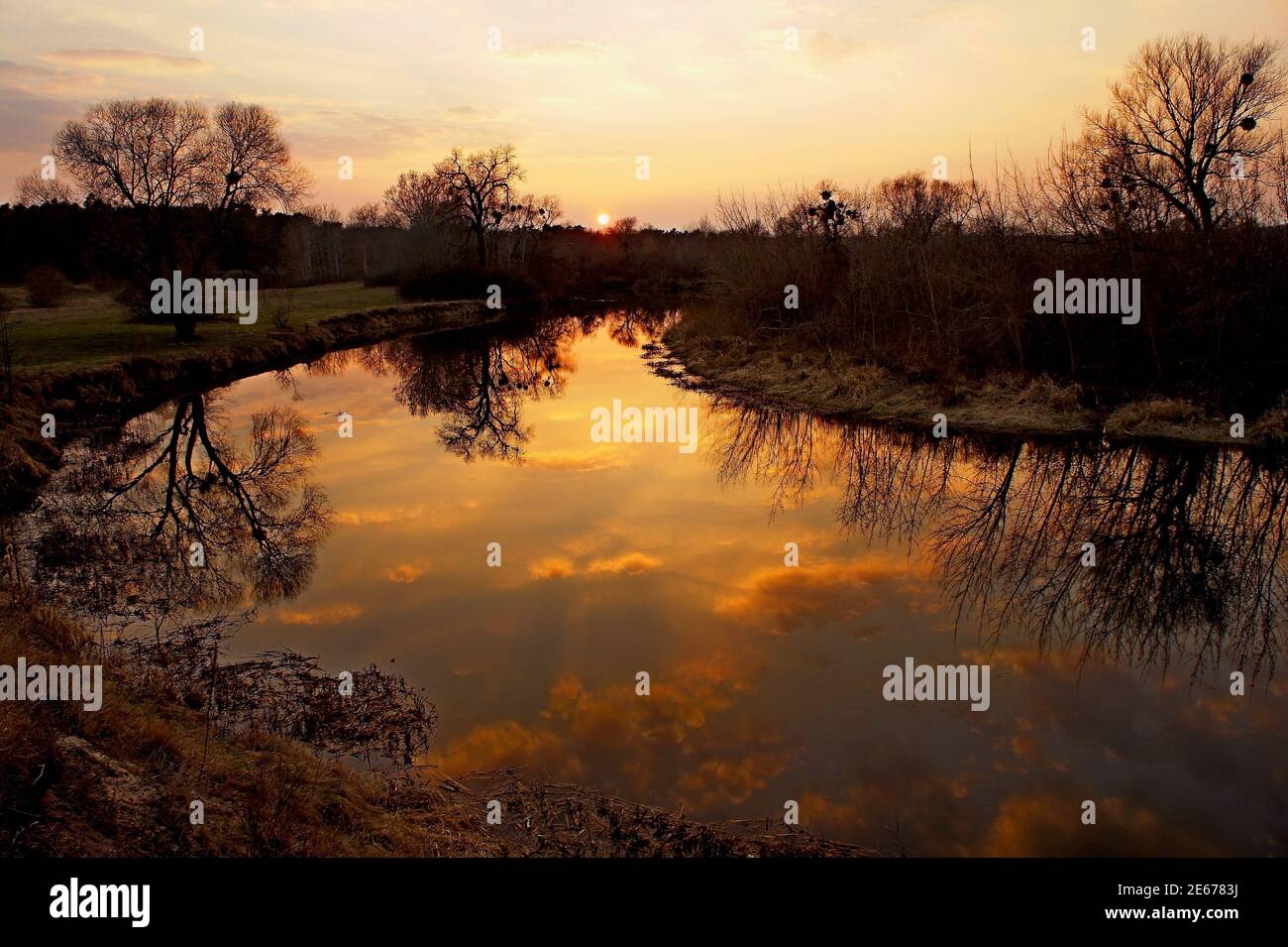 Erstaunlicher goldener Sonnenuntergang über dem Fluss mit Spiegelreflexion Von Wolken im Wasser Stockfoto